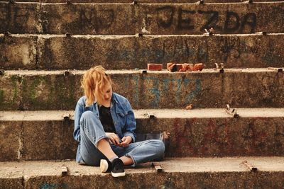 Full length of young woman sitting outdoors