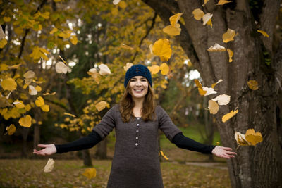 Portrait of young woman standing against trees