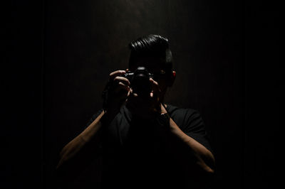 Man photographing with camera in darkroom