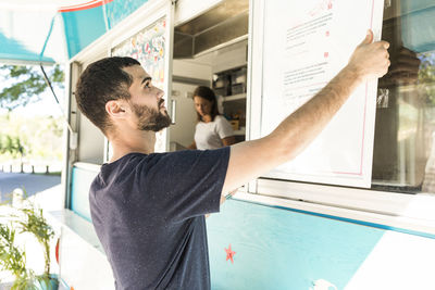 Confident young male salesman positioning menu placard on food truck