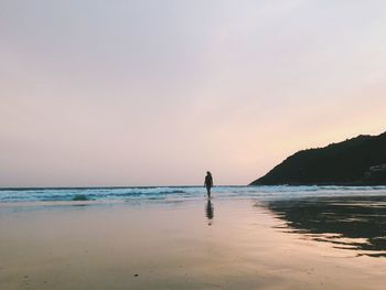 Silhouette man on beach against sky during sunset