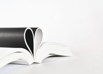 Pages of book in heart shape over white background