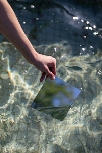 Cropped hand of woman holding glass in swimming pool