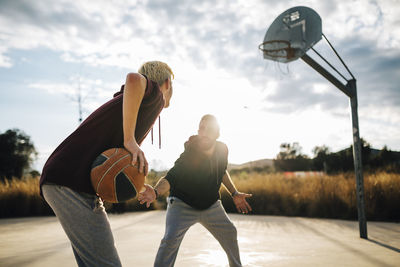 Two young men playing basketball on an outdoor court