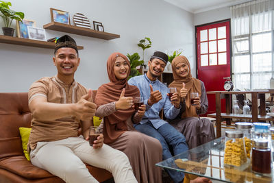Portrait of smiling couples gesturing while holding drink glass at home