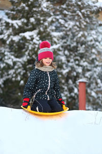 Winter portrait of a girl with a plastic sled sliding on a snowy slope 