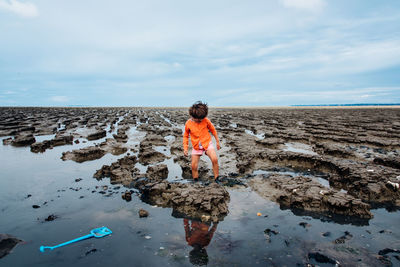 Girl standing on mud against sky