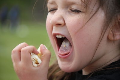 Close-up of girl eating popcorns while standing outdoors