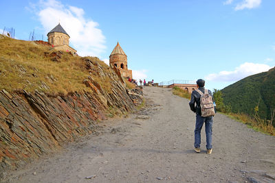 Visitor climbing up to the medieval gergeti trinity church, stepantsminda town, kazbegi, georgia