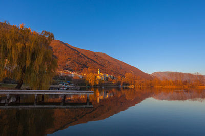 Small village overlooking the lake during an autumn sunset with a willow tree