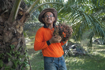 Portrait of smiling man holding fruit at farm