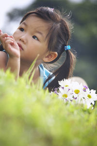 Girl with bunch of flowers lying on grassy field at park