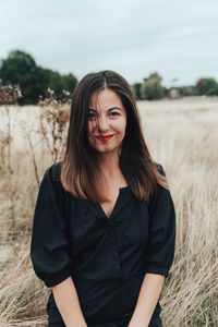 Portrait of smiling young woman standing on field