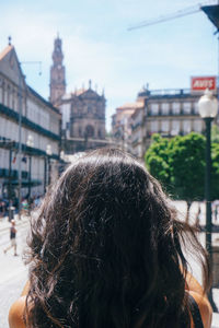 Rear view of woman in city against sky