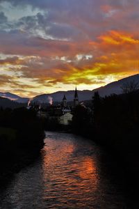 Scenic view of river against cloudy sky during sunset