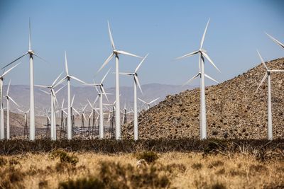 Windmills on field against sky