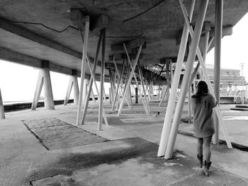 Rear view of woman walking under bridge