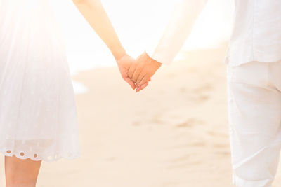 Low section of man and woman on sand at beach