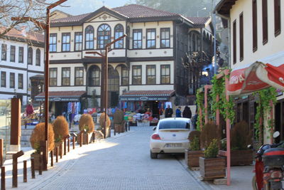 People walking on road by buildings in city