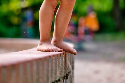 Low section of boy standing on retaining wall