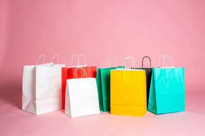 A set of bright colored paper bags stands on a pink background