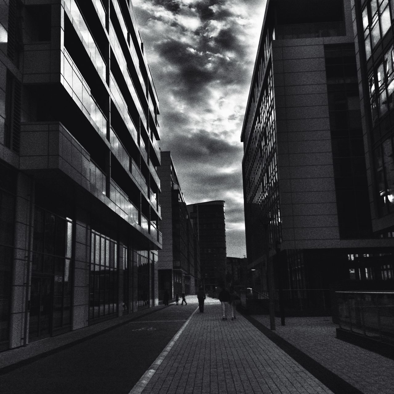 architecture, building exterior, built structure, city, the way forward, sky, building, diminishing perspective, street, city life, cloud - sky, residential building, vanishing point, residential structure, outdoors, cloud, incidental people, narrow, day, office building