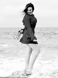 Full length portrait of young woman standing on beach