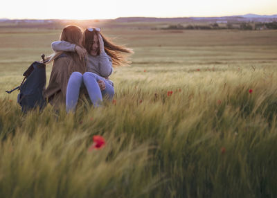 Two women holding hands at sunset in the field