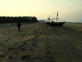 Silhouette man on beach against sky during sunset