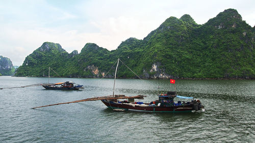 People on boat sailing in river against sky