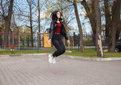 Full length of woman jumping against trees