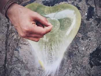 Cropped hand above burst heart shape balloon