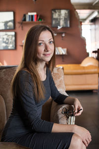 Portrait of smiling young woman sitting on armchair