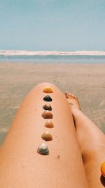 Midsection of woman relaxing on beach against sky