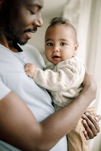 Smiling father carrying male toddler at home