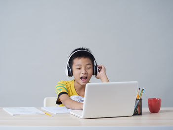 Boy using mobile phone while sitting on table