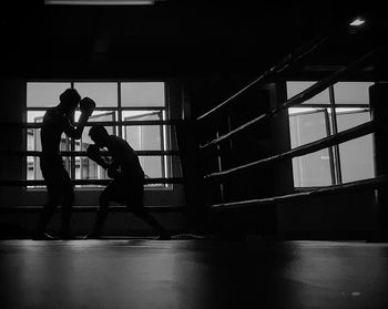 Side view of silhouette men boxing at ring