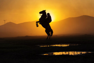 Silhouette man on mountain against sky during sunset