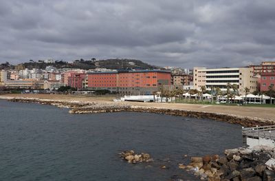 Buildings by sea against sky