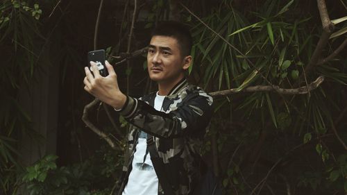 Young man photographing while standing on camera