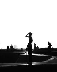 Silhouette people standing on road against clear sky