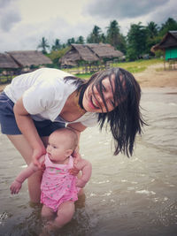 Happy mother holding daughter while standing in lake