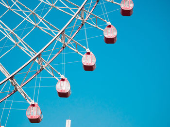 Low angle view of ferris wheel against clear blue sky