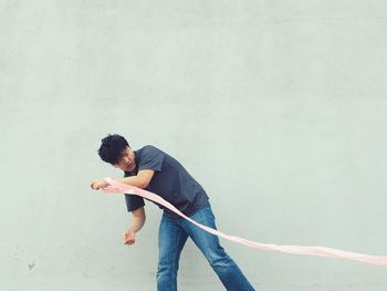 Man holding ribbon while standing against gray wall