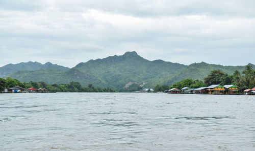 Scenic view of river by mountains against sky