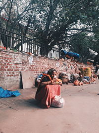 Rear view of people sitting on sidewalk in city