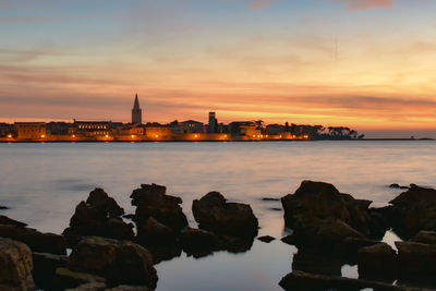 Scenic view of sea and buildings against sky during sunset