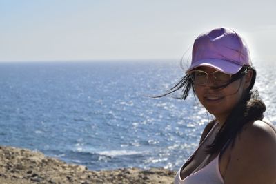 Portrait of smiling young woman in sea against sky