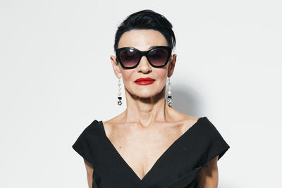 Portrait of young woman wearing sunglasses against white background