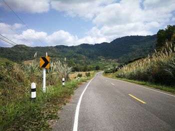 Road leading towards mountains against sky